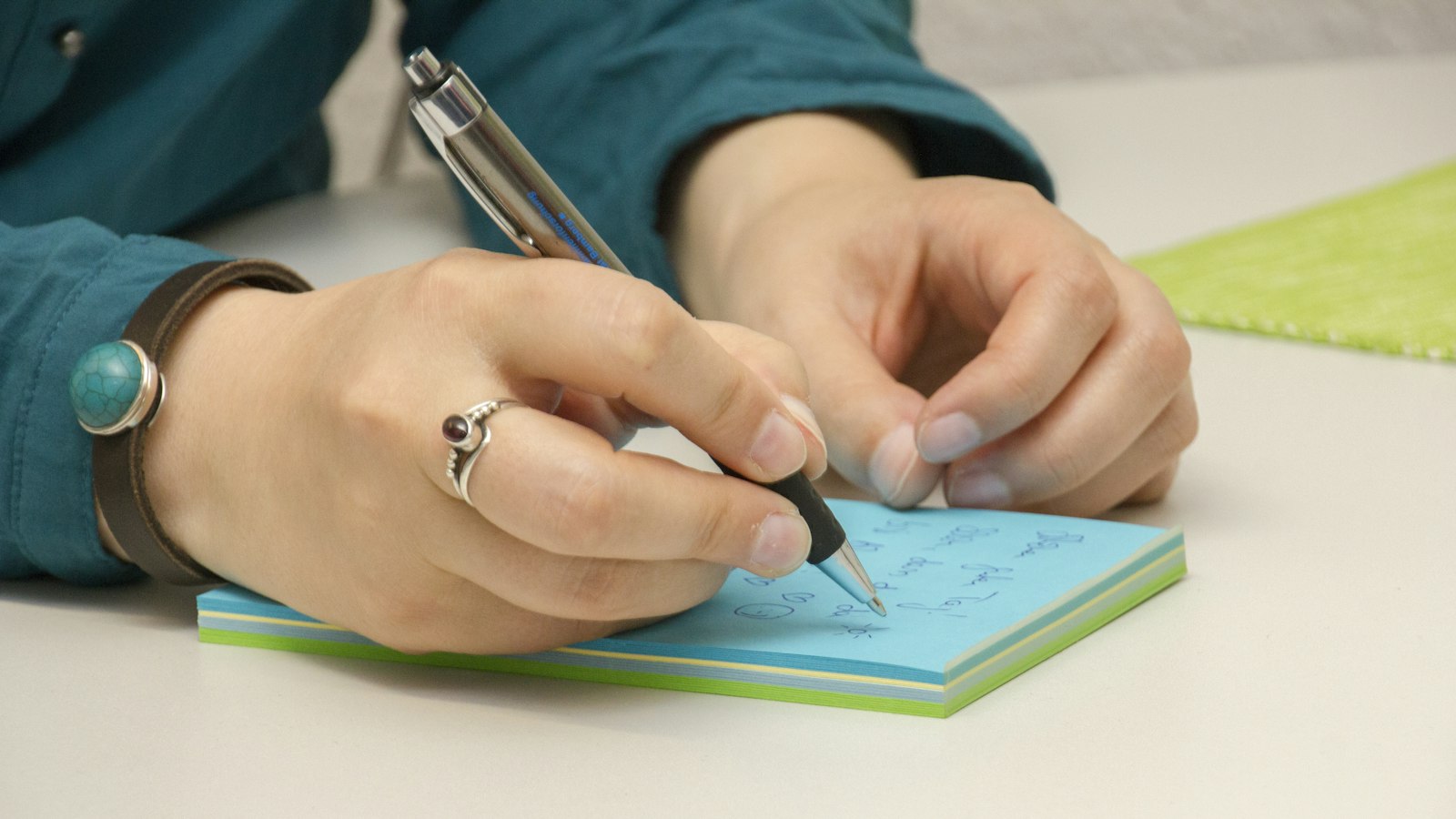 付箋にやることを書き出す女性の手元