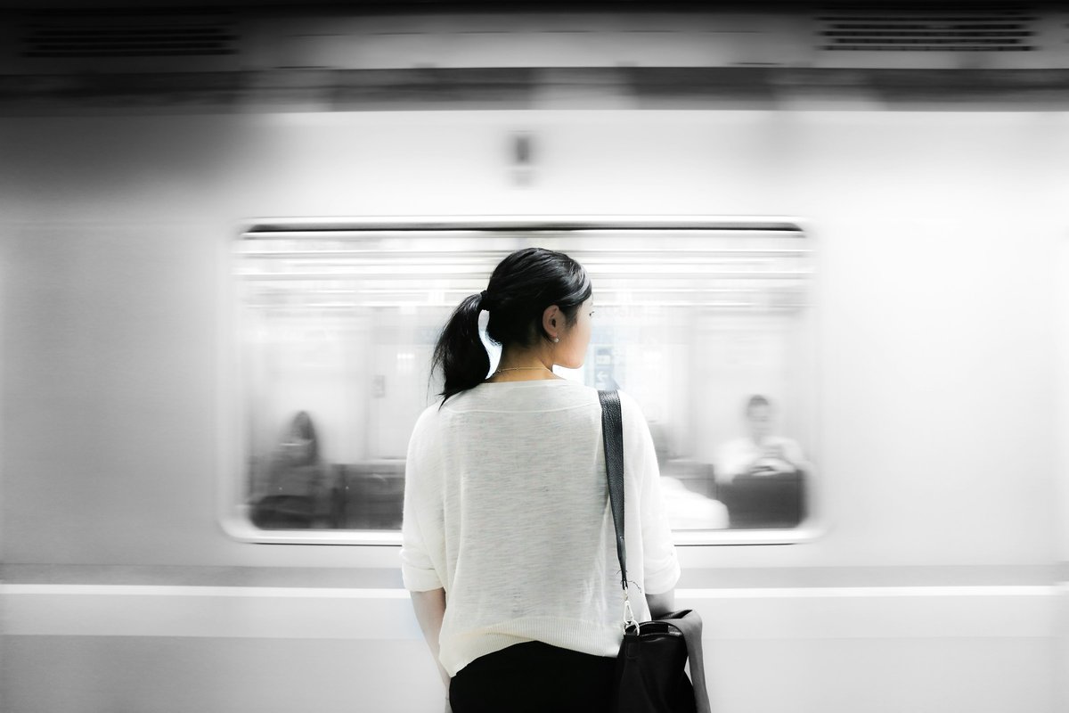 駅のホームで電車を待つ女性の後ろ姿