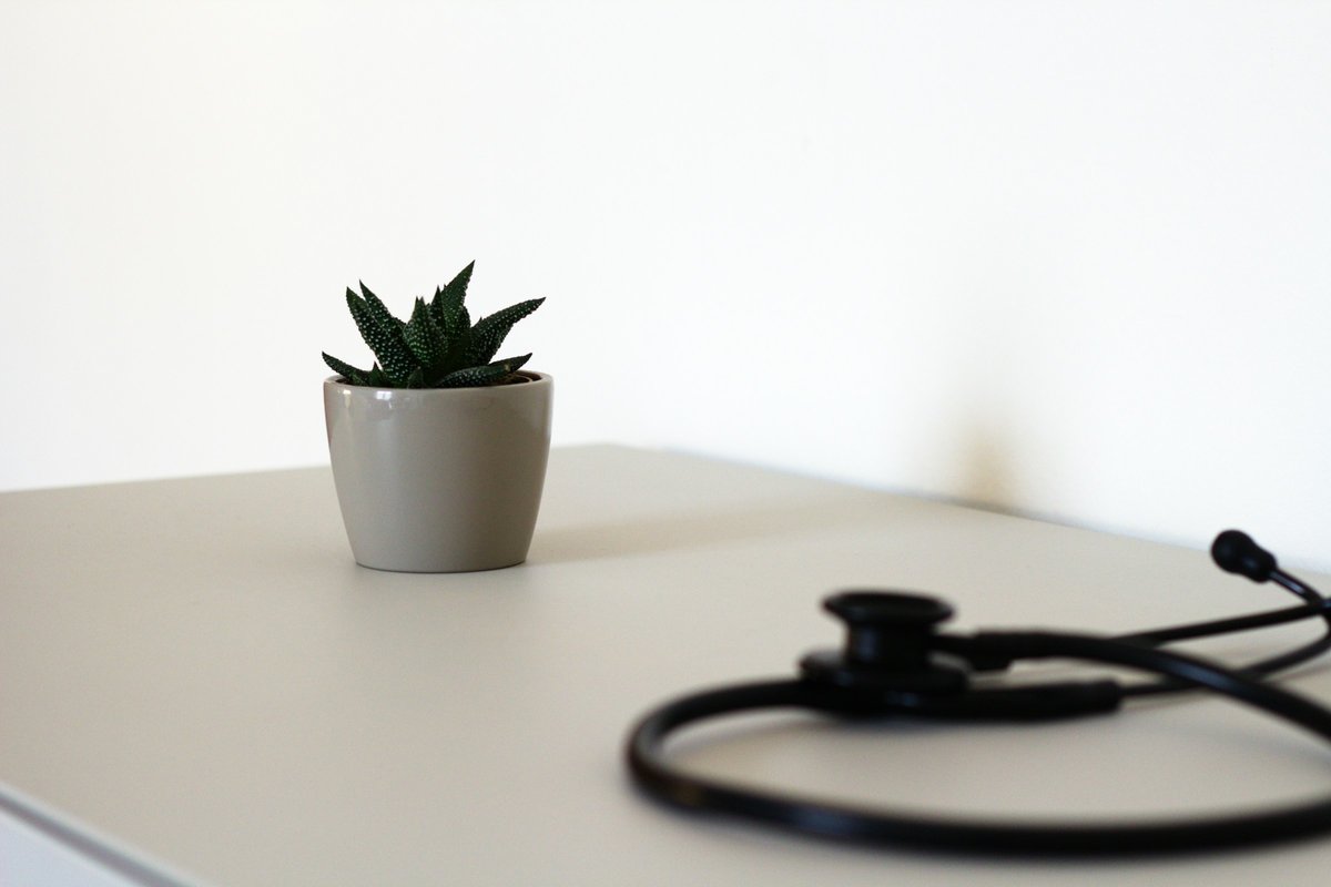 白い机に置いた聴診器と小さな観葉植物