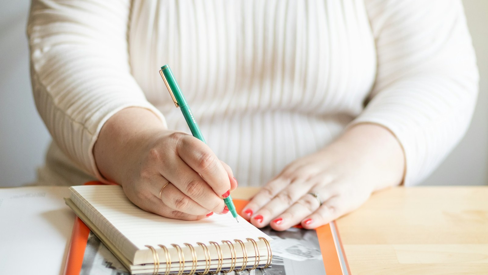 ノートにペンで書き込む女性の手元