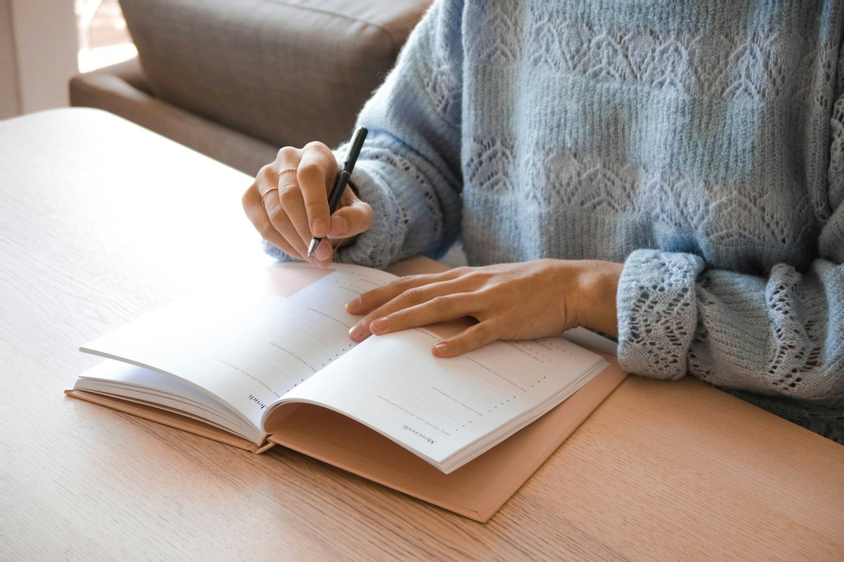 手帳に予定を書き込む女性の手元
