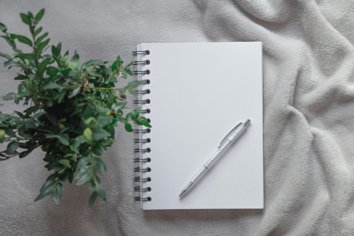 白いブランケットの上のノートとペンと観葉植物