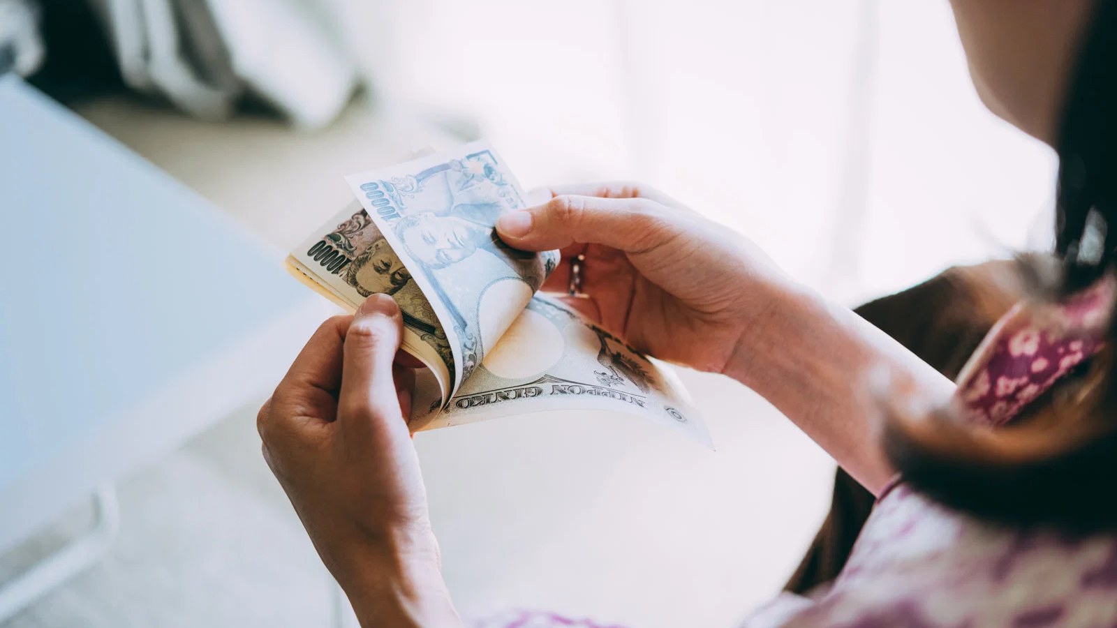 給与明細を見ながら千円札を数える女性の手元