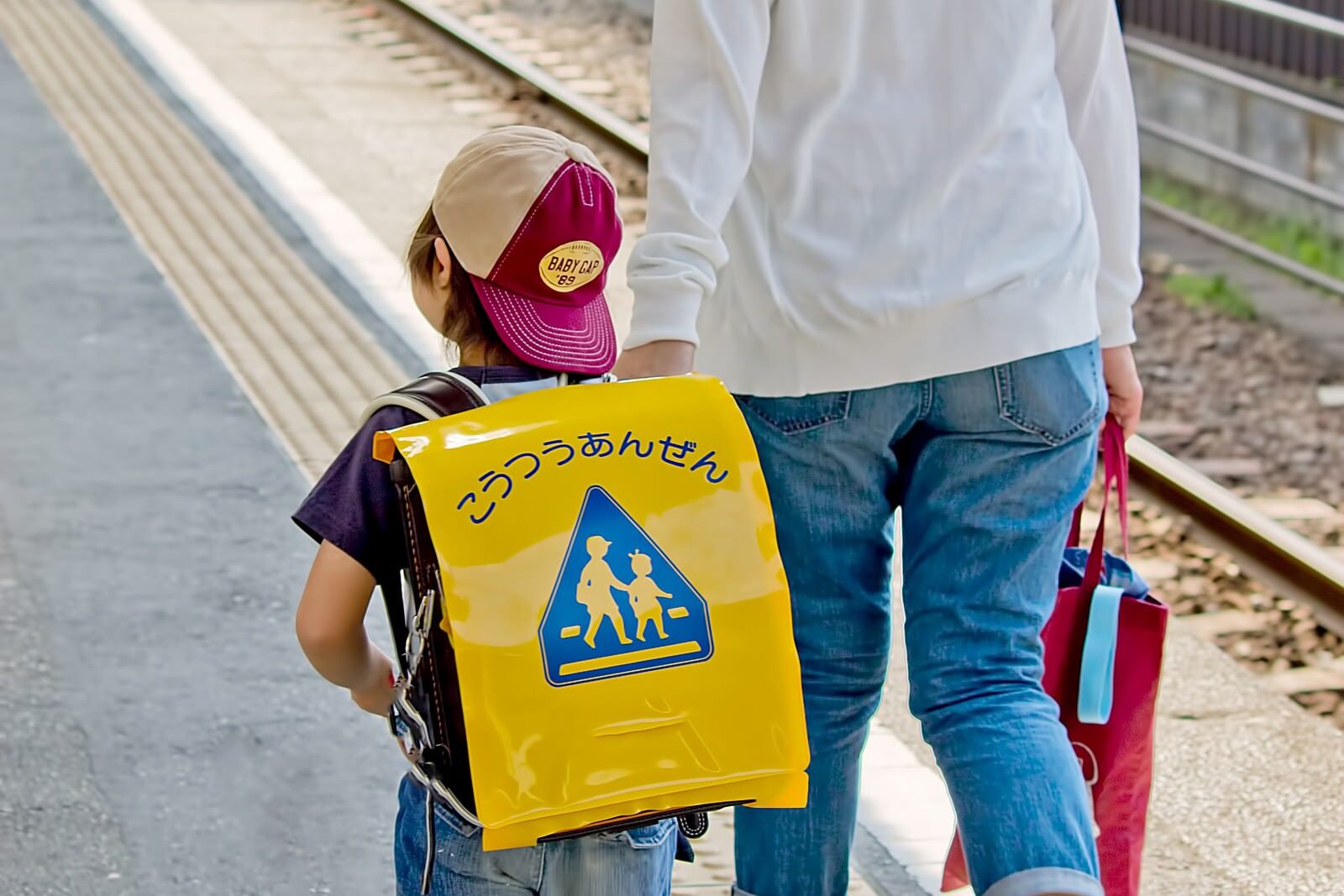 ランドセルの子どもと大人が並んで歩く後ろ姿