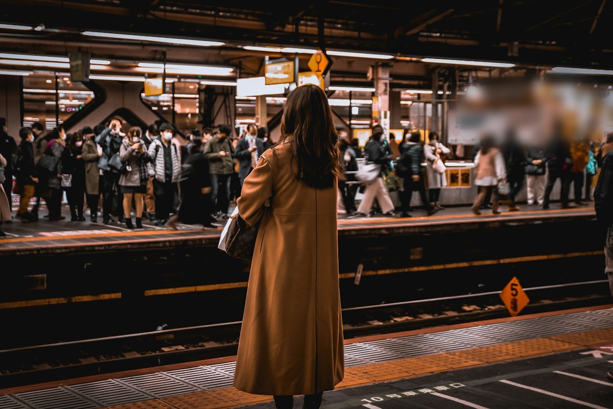 駅のホームで電車を待つ女性の後ろ姿