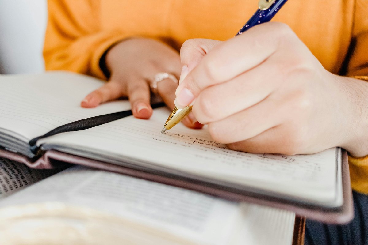 手帳にペンで書き込む女性の手元