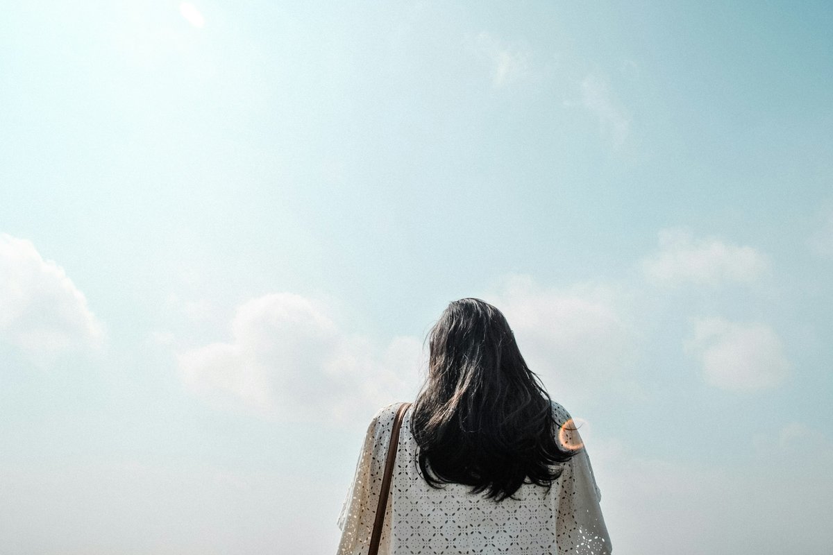 青空を見上げる女性の後ろ姿