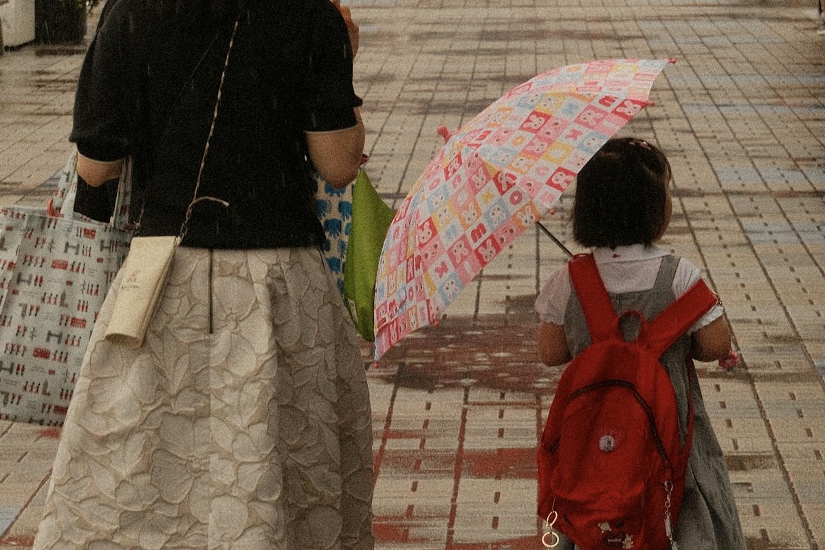 雨の日に子どもと歩く母親の後ろ姿