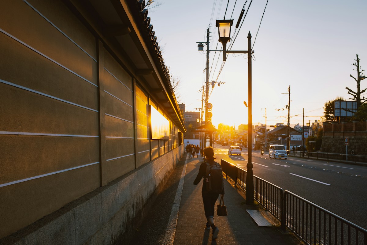 夕日の歩道を歩く人の後ろ姿